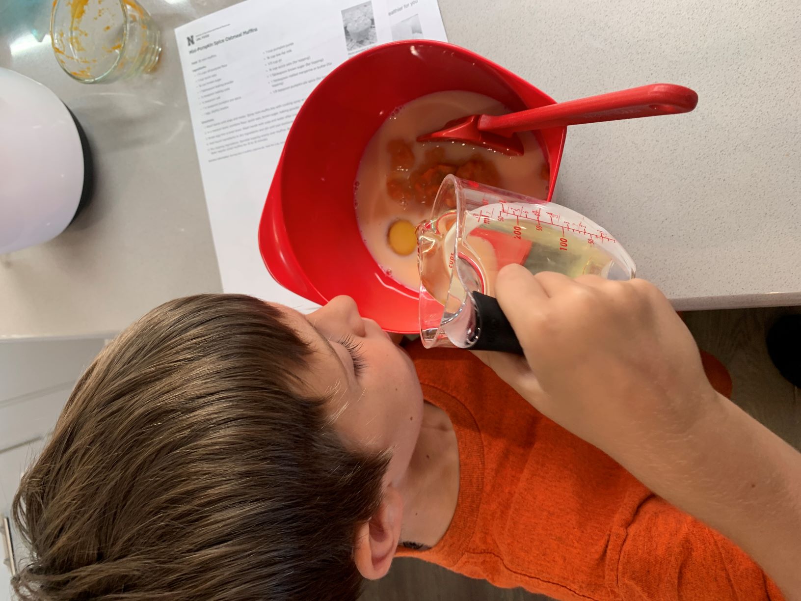 child pouring oil into bowl