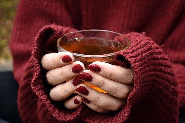 woman's hands holding hot cup of tea