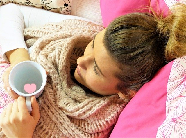 young woman wrapped up warmly, sipping hot beverage