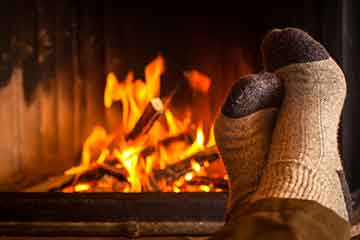 fireplace burning wood with feet crossed in cozy socks in the foreground