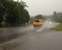 car driving over a flooded road spraying water