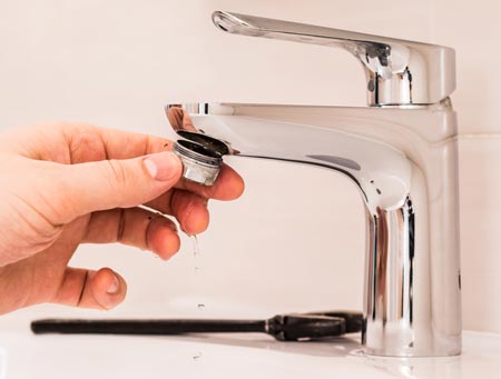 person installing a faucet aerator