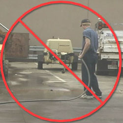 worker hosing down outside work areas with a big red stop sign placed on top