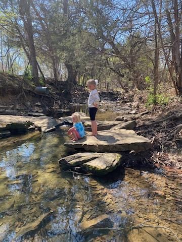 kids sitting on boulders on creek bank