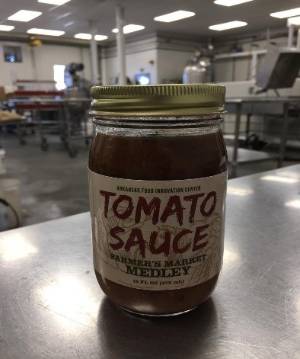 Mason jar filled with processed tomato sauce with a label that says tomato sauce