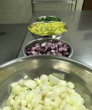 Chopped vegetables in metal bowls on top of a metal counter