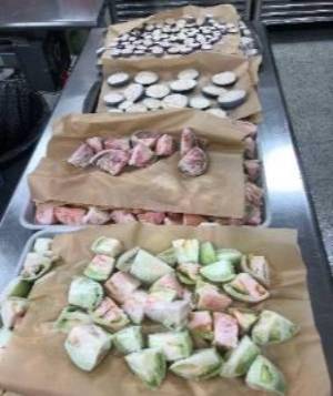 Chopped frozen vegetables piled on top of each other separated by wax paper