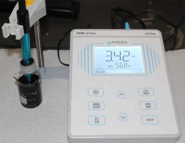A beaker of grape juice hooked up to a pH meter with a pH of 3.42 displayed on the screen
