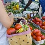 woman holding basket of veggies shopping at a farmer's market