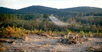 helicopter flying through forest performing an aerial application