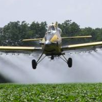 plane applying spray to a field