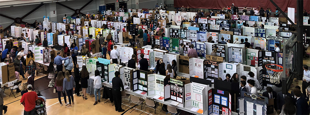 auditorium filled with people looking at science projects