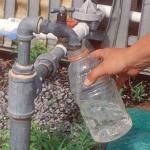 Person fills a water bottle for sample