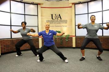 Three African American women with arms outstretched to their sides and slightly lunging to their right.