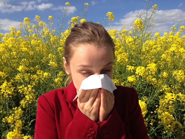 person sneezing into tissue surrounded by flowers