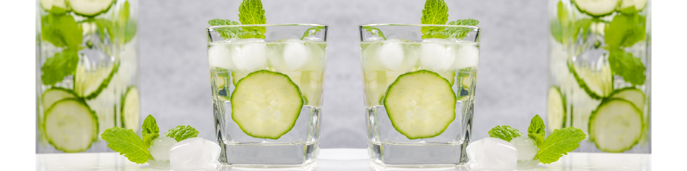 slices of cucumber and sprigs of mint in a couple glasses of ice water