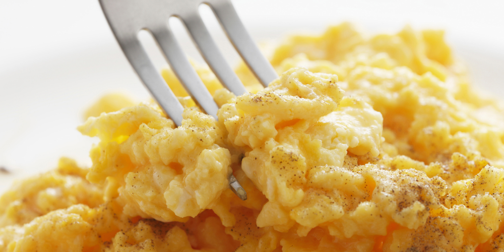 fork lifting a bit of scrambled eggs from a mound of scrambled eggs