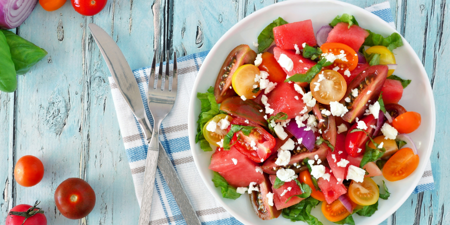 large chopped tomatoes and watermelon mixed slices of onion garnished with minced herb and cheese