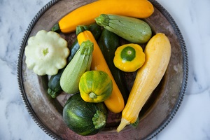 Bowl of different types of summer squash sitting on a marble table