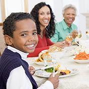 Family around the dinner table sharing a meal of roasted turkey, sautéed zucchini, and steamed broccoli