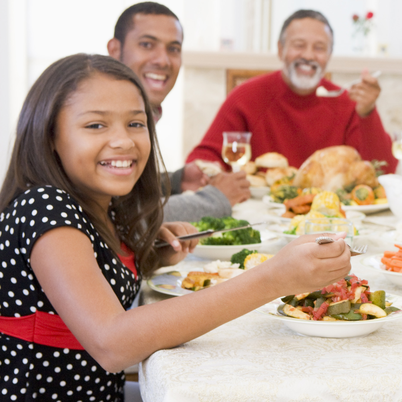 Family around the dinner table sharing a meal of roasted turkey, sautéed zucchini, and steamed broccoli