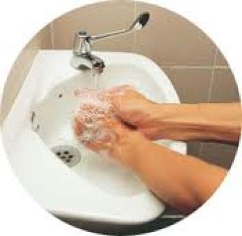Person with soapy hands over a white sink rinsing under a faucet.
