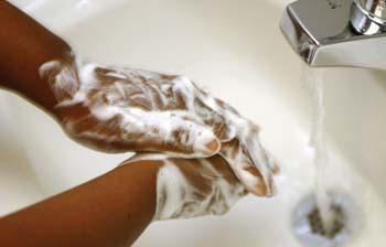 Someone's hands covered with soap and water coming out of the faucet for rinsing. 