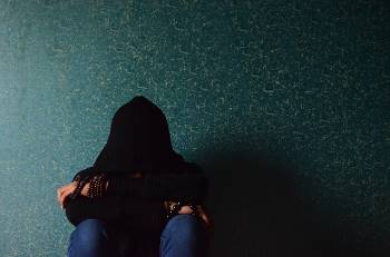 Man sitting on floor with hood over his face