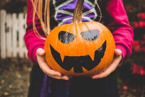 Child holding painted pumpkik