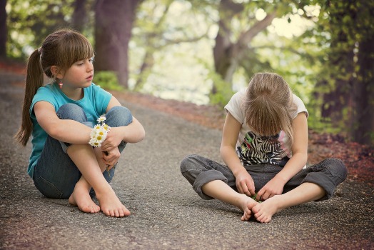 Two girls sitting on sidewalk arguing