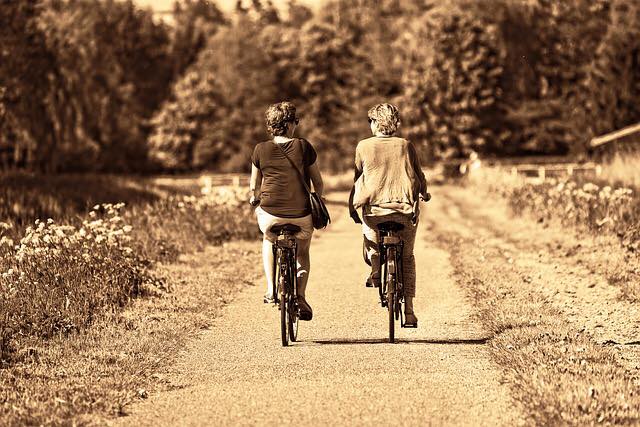 two women riding a bike on a trail