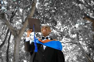 Male graduate holding up graduation cap