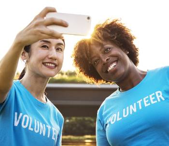 two women taking a selfie with shirts that say volunteer