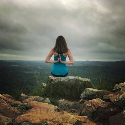 woman sitting on rock in yoga pose