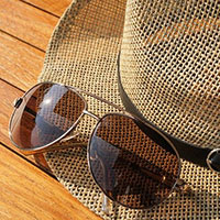Sunglasses on rim of a light brown hat.