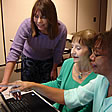 Registering for in-service on the computer. Three women working on a computer.